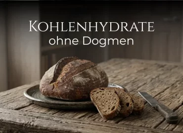 Kohlenhydrate ohne Dogmen: Ein Sauerteigbrot liegt auf einem rustikalen Tisch. Daneben das Brotmesser.