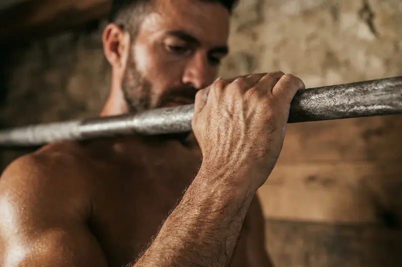 Nahaufnahme vom Griff an einer Klimmzugstange: Die schwitzenden Hände eines Mannes im rustikalen Home-Gym (Eigengewichtstraining/Calisthenics).