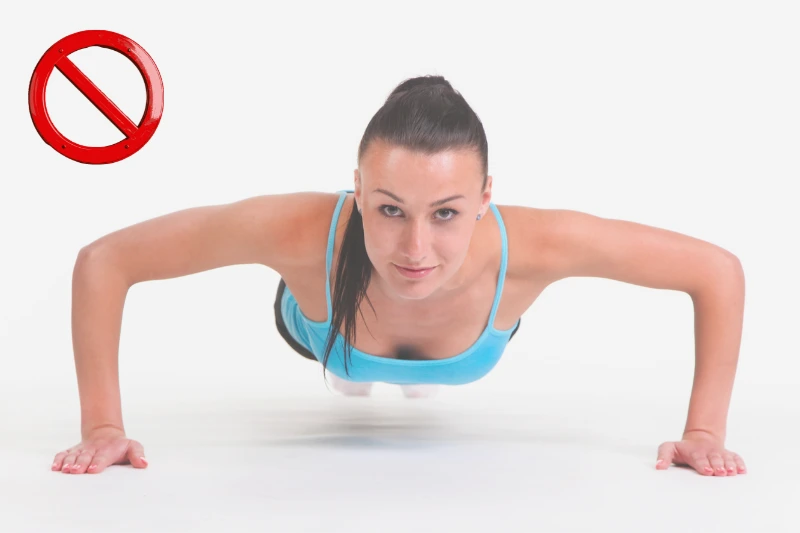 Liegestütze in der falschen Ausführung: Bild einer jungen Frau, die Liegestütze mit weit auseinandergestellten Armen macht.