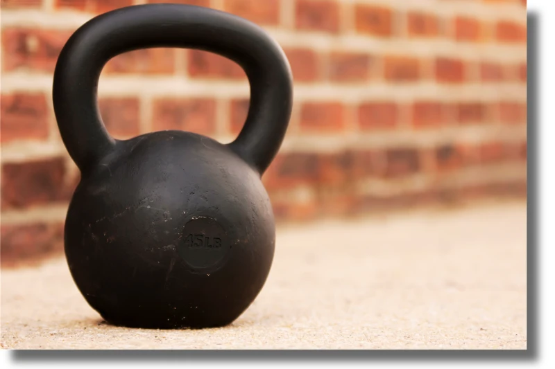 Eine Kettlebell vor einer Backsteinmauer. Symbolbild für Sophrosyne: Der Mäßigung im Training.