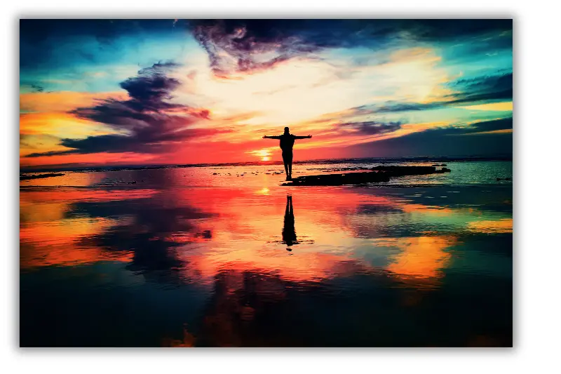 Symbolbild für Souveränität: Person am Meer vor einem bunten Himmel, streckt die Arme aus.